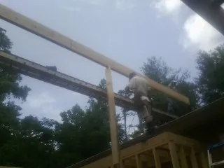 Carpenter setting a ridge beam over a new addition frame — Ice Dam Removal by Roofing Brothers in Port William