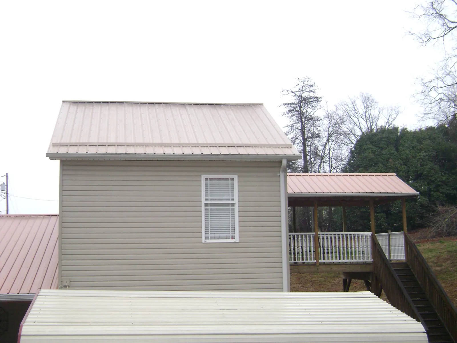 Tan metal roofs on a two story addition and attached porch, from a Roof Replacement job in Port William